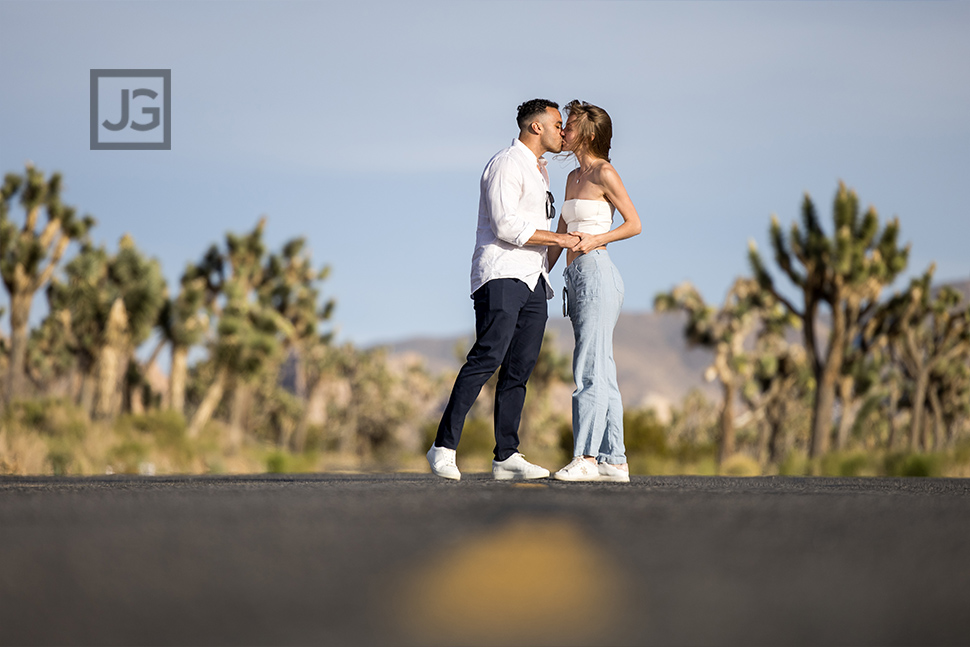 Newly engaged couple kissing on a road